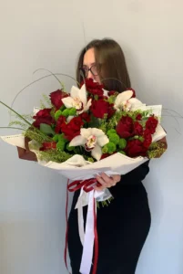 Bukiet z róż i białych orchidei z zielenią dekoracyjną, przewiązany wstążką