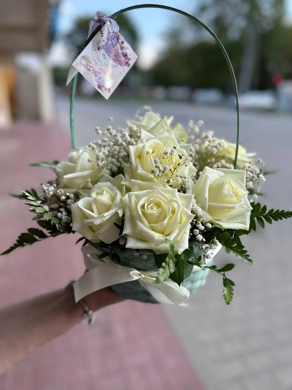 Koszyk z białymi różami i gipsówką ozdobiony kokardką