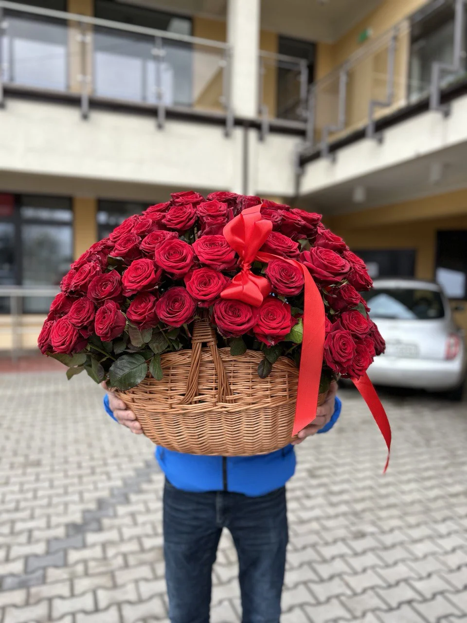 100 świeżych czerwonych róż w dużym wiklinowym koszu z kokardą