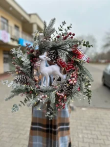 Zimowa dekoracja z szyszkami, jeleniem i czerwonymi akcentami – świąteczny wieniec na drzwi